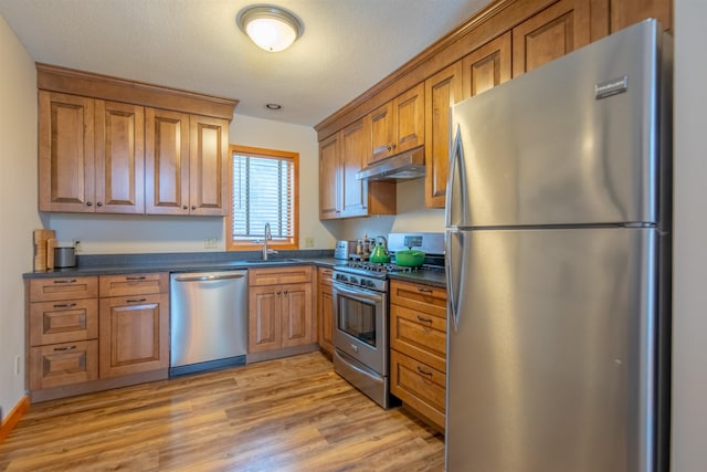 kitchen with stainless steel appliances, sink, and light wood-type flooring