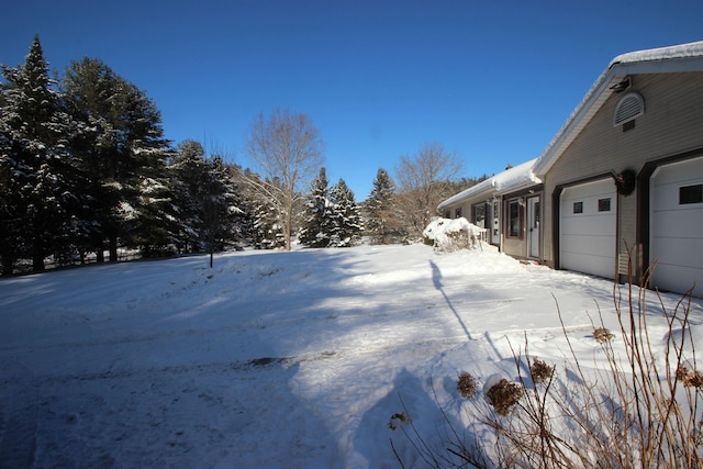 snowy yard featuring a garage