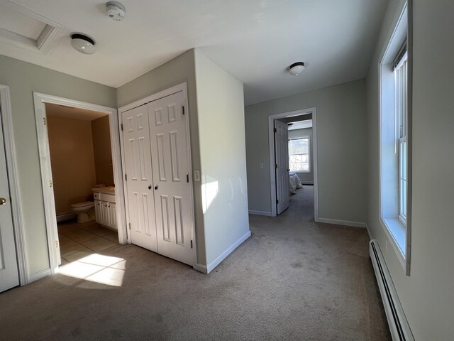 interior space featuring a baseboard heating unit and light carpet