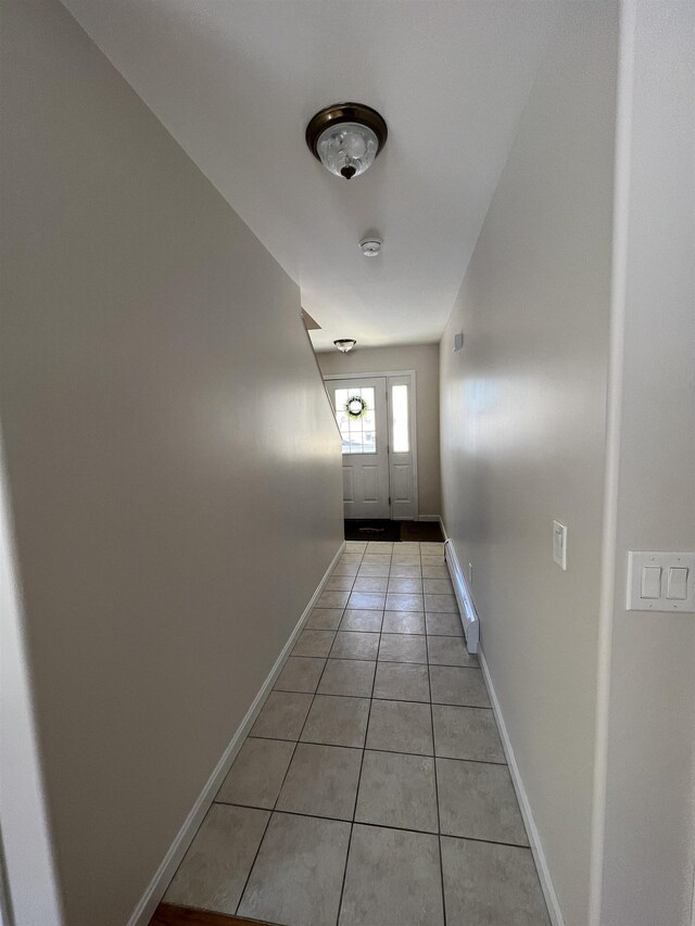 doorway with light tile patterned floors and baseboard heating