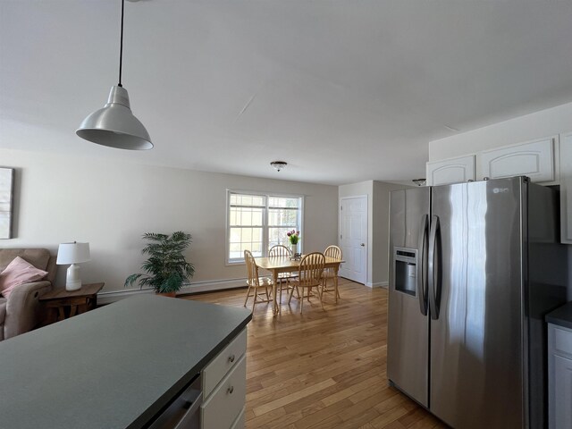 kitchen featuring white cabinetry, stainless steel fridge, light hardwood / wood-style flooring, and pendant lighting