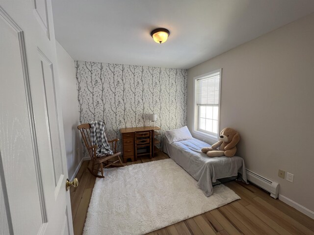 bedroom featuring hardwood / wood-style flooring and a baseboard heating unit