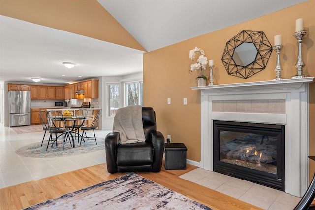 living room with lofted ceiling, a fireplace, and light hardwood / wood-style floors