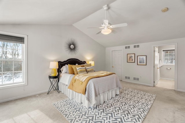 bedroom with ceiling fan, light colored carpet, connected bathroom, and vaulted ceiling