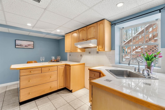 kitchen featuring sink, light tile patterned floors, tile counters, kitchen peninsula, and backsplash