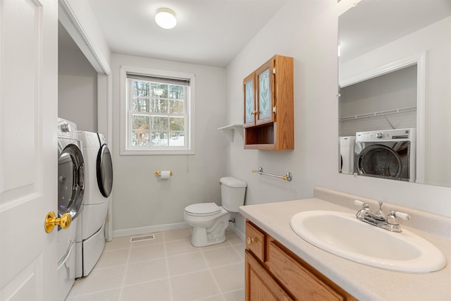 bathroom featuring washing machine and clothes dryer, vanity, toilet, and tile patterned flooring