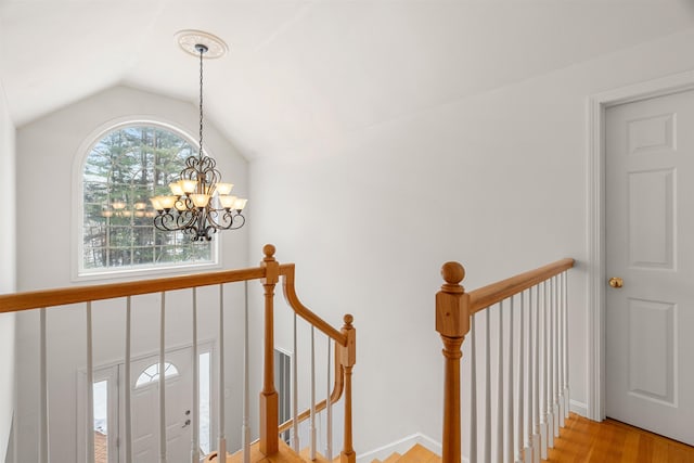 staircase featuring wood-type flooring, vaulted ceiling, and a notable chandelier