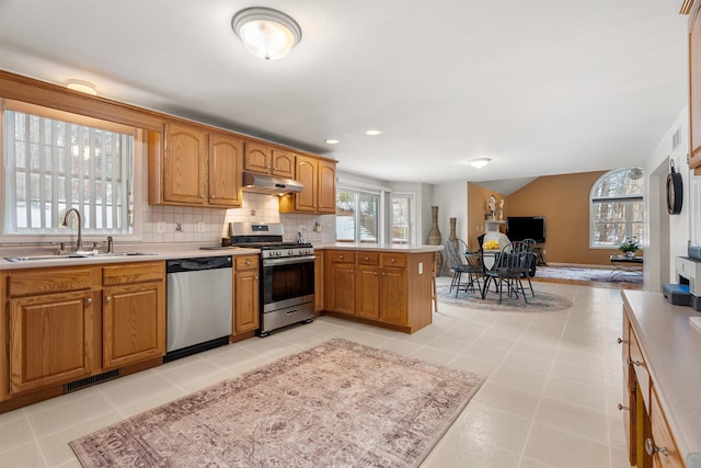 kitchen featuring sink, appliances with stainless steel finishes, backsplash, light tile patterned flooring, and kitchen peninsula