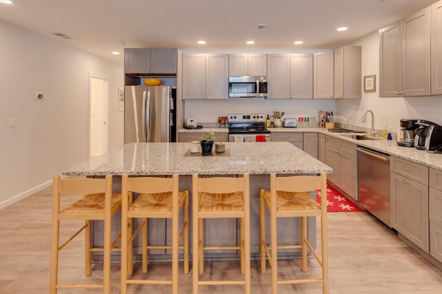 kitchen featuring light stone counters, stainless steel appliances, a breakfast bar, and a center island