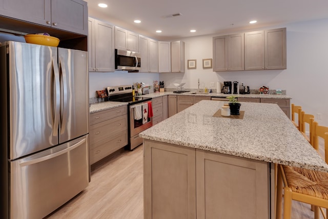 kitchen featuring stainless steel appliances, a center island, a breakfast bar area, and gray cabinetry