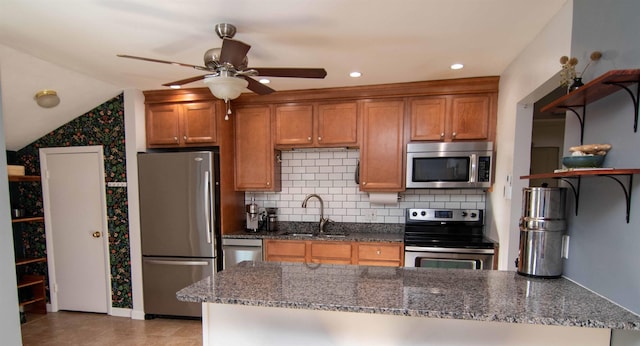 kitchen featuring appliances with stainless steel finishes, sink, backsplash, and dark stone counters