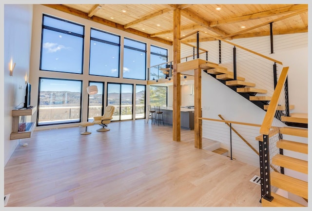 stairway with a towering ceiling, beam ceiling, hardwood / wood-style floors, and wooden ceiling