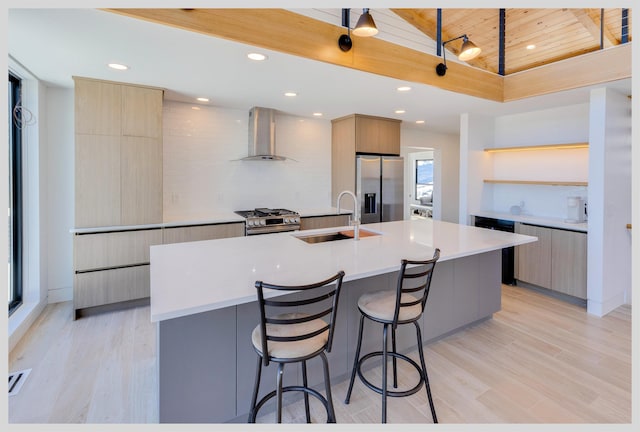 kitchen with a large island, wall chimney range hood, wood ceiling, sink, and appliances with stainless steel finishes