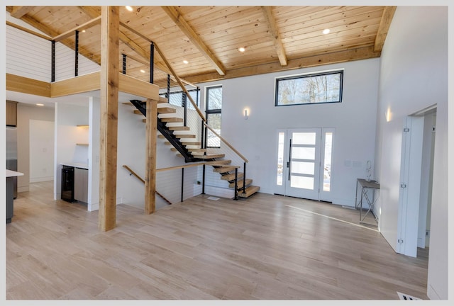 unfurnished living room with beamed ceiling, light hardwood / wood-style flooring, and wooden ceiling