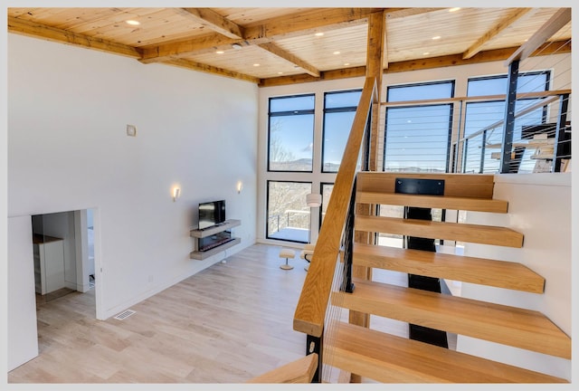 stairs featuring wood-type flooring, wooden ceiling, and beamed ceiling