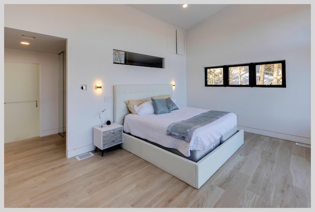 bedroom featuring high vaulted ceiling and light hardwood / wood-style flooring