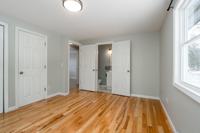 unfurnished bedroom with connected bathroom and light wood-type flooring