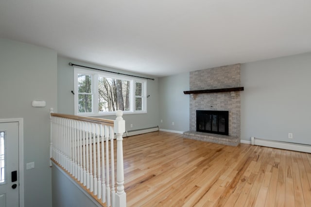 unfurnished living room with a fireplace, a baseboard radiator, and hardwood / wood-style floors