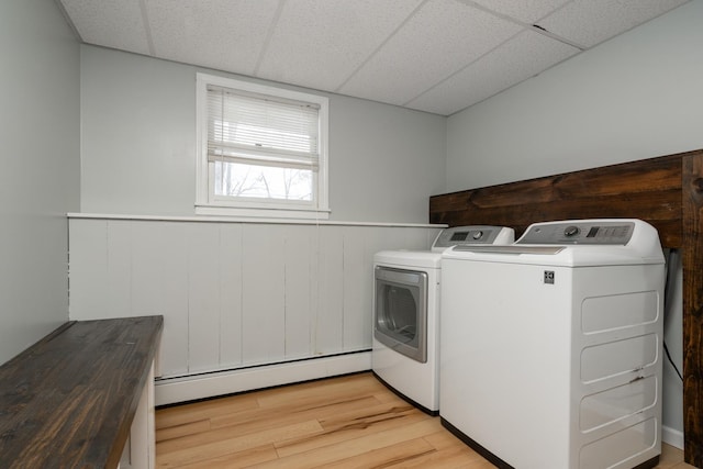 laundry room featuring a baseboard heating unit, washing machine and clothes dryer, and light wood-type flooring