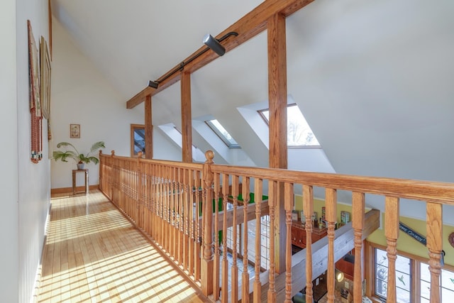 hall featuring beamed ceiling, a skylight, and high vaulted ceiling