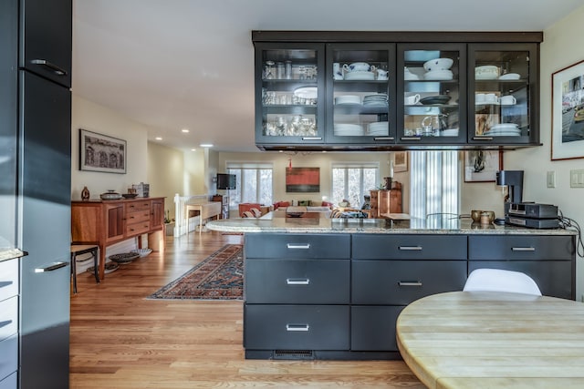 bar featuring light stone countertops and light wood-type flooring