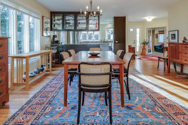 dining space featuring sink, a notable chandelier, and light hardwood / wood-style flooring