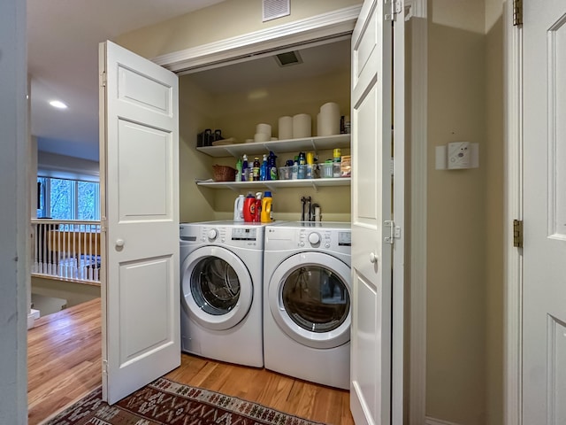 clothes washing area with separate washer and dryer and light wood-type flooring