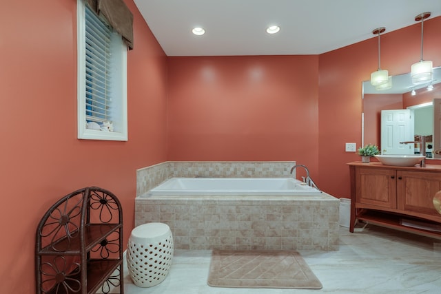 bathroom featuring tile patterned flooring, vanity, and tiled bath