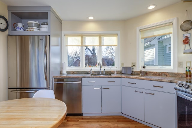 kitchen with sink, light hardwood / wood-style flooring, stainless steel appliances, and a healthy amount of sunlight