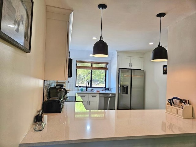 kitchen featuring white cabinetry, appliances with stainless steel finishes, and hanging light fixtures