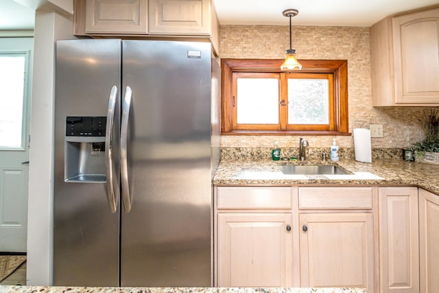 kitchen with sink, stainless steel fridge, decorative backsplash, light brown cabinetry, and decorative light fixtures