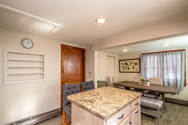 kitchen featuring light stone countertops, a kitchen island, light hardwood / wood-style floors, and baseboard heating