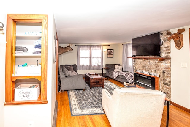 living room with hardwood / wood-style floors and a stone fireplace