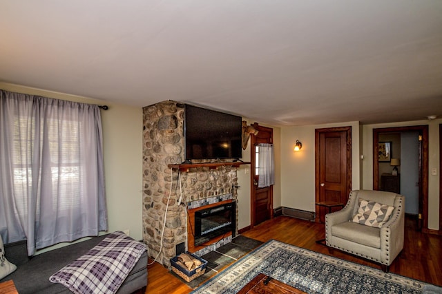 living room featuring a stone fireplace and dark hardwood / wood-style flooring