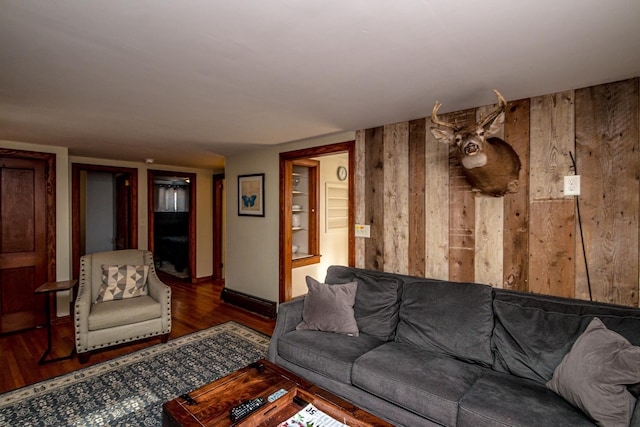 living room with dark hardwood / wood-style flooring and wood walls