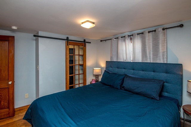 bedroom featuring a barn door and hardwood / wood-style floors