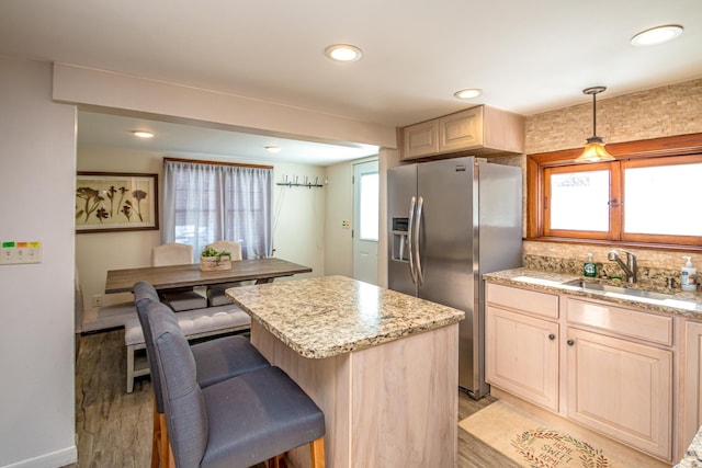 kitchen with sink, tasteful backsplash, stainless steel fridge with ice dispenser, a kitchen island, and pendant lighting