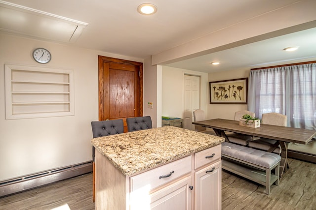 kitchen with light stone counters, a baseboard radiator, a center island, and wood-type flooring