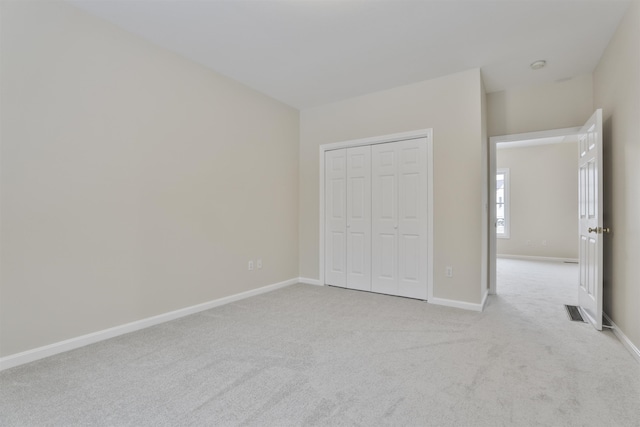 unfurnished bedroom featuring light carpet and a closet