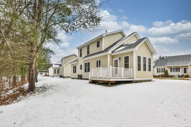 snow covered rear of property with a deck