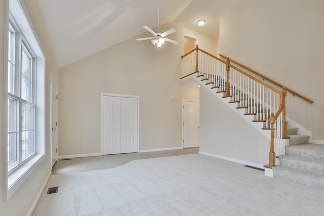 unfurnished living room with high vaulted ceiling, light colored carpet, and ceiling fan