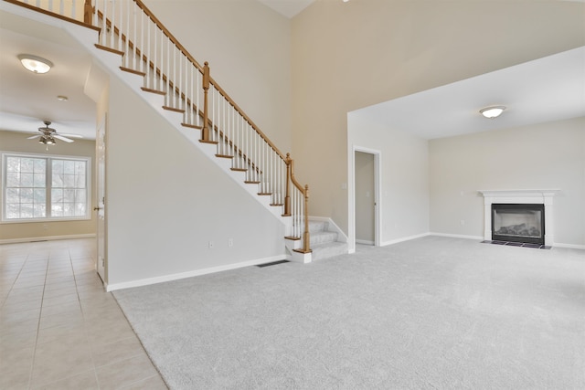 unfurnished living room featuring a high ceiling, light tile patterned floors, and ceiling fan