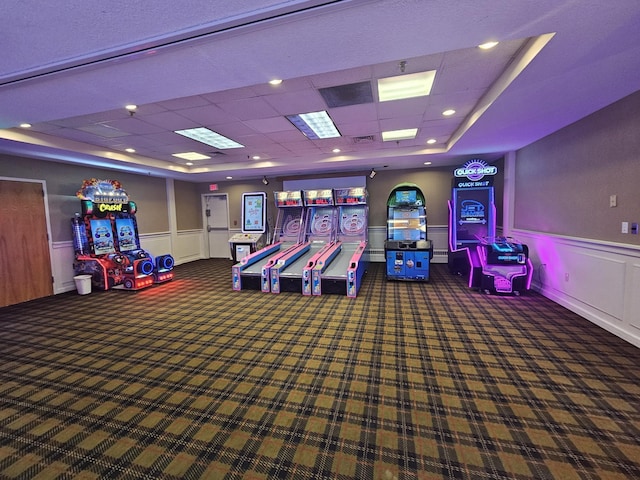 playroom with a tray ceiling and dark colored carpet