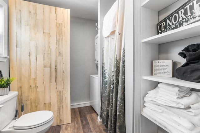 bathroom featuring hardwood / wood-style floors, toilet, and stacked washer / dryer