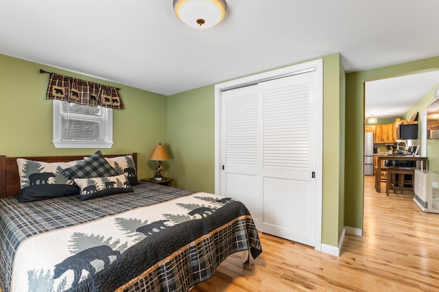 bedroom with sink, stainless steel fridge, light hardwood / wood-style floors, and a closet