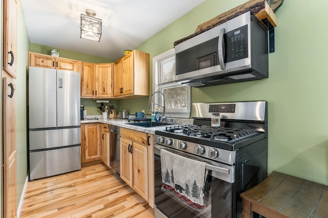 kitchen featuring stainless steel appliances, sink, light brown cabinets, and light hardwood / wood-style floors