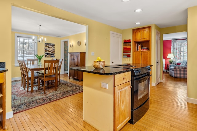 kitchen with pendant lighting, light hardwood / wood-style floors, a kitchen island, and electric range