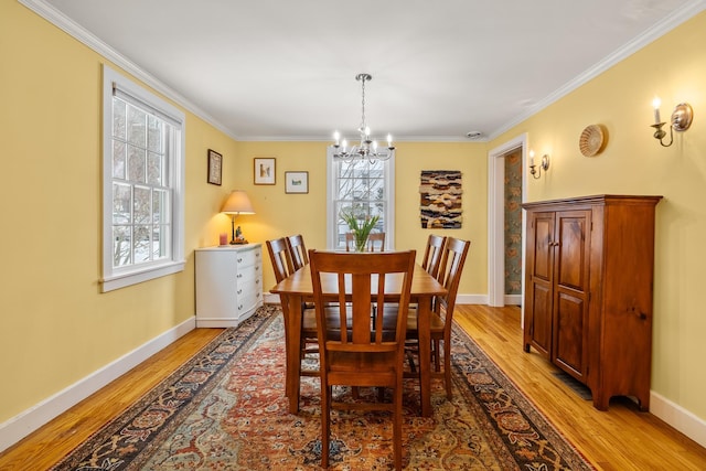 dining space with a notable chandelier, ornamental molding, and light wood-type flooring