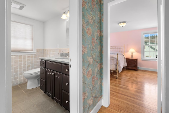 bathroom with hardwood / wood-style flooring, vanity, toilet, and tile walls