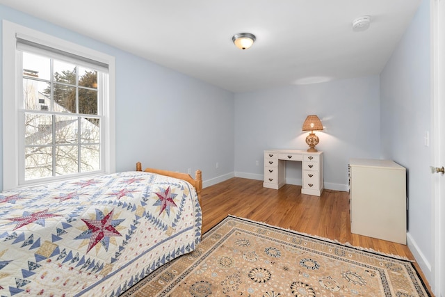 bedroom with multiple windows and light hardwood / wood-style flooring